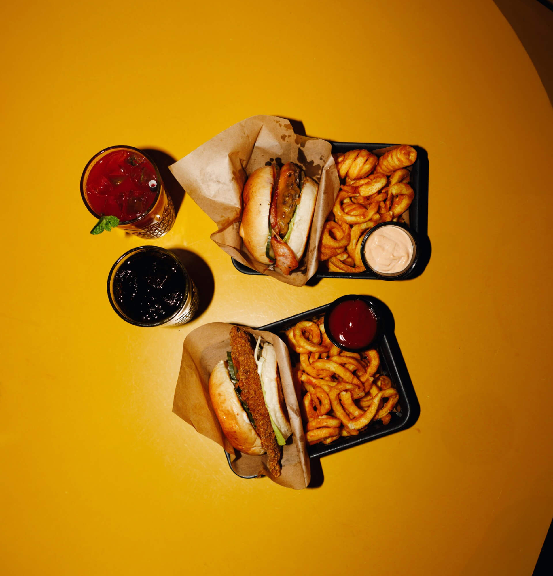 To burgere fra Camping Bar i Malmø med tilhørende pomfritter, dip og drinks